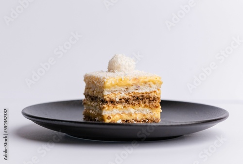 Delicious slice of Plazma cake on a matte dark grey plate on a white background