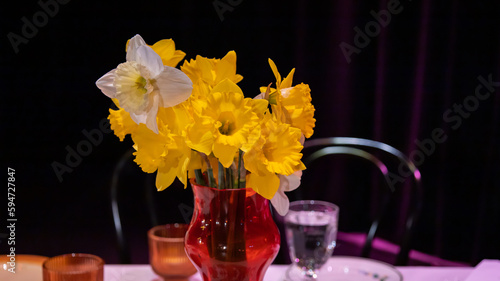 bukiet kwiatów narcyzy w czerwonym dzbanku stojącym na stole zbliżenie 