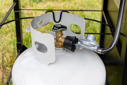 Propane gas cylinder with hose and regulator for BBQ grill. Grilling safety, LPG equipment inspection and storage
