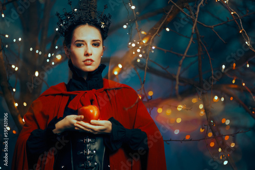 Evil Queen Holding a Red Poisonous Apple as Bait. Fantasy fairy tale villain planning a witchcraft trick 