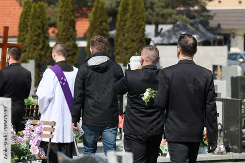 Ksiądz katolicki w komży z fioletowa stułą podczas celebracji pogrzebu. 