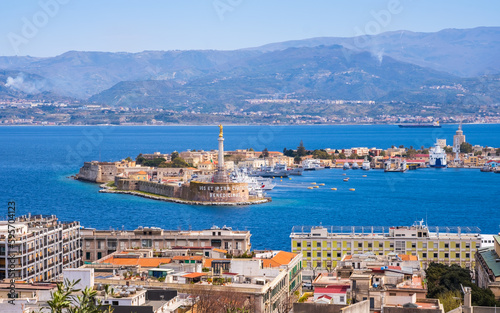 The Strait of Messina between Sicily and Italy. View from Messina town with golden statue of Madonna della Lettera and entrance to harbour. Calabria coastline in background