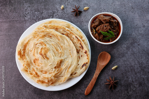 Beef curry with Kerala parathas porotta roti parotta barotta naan layered flatbread made from maida or whole wheat flour. Eat with spicy Asian chicken beef egg curry gravy. Indian food.