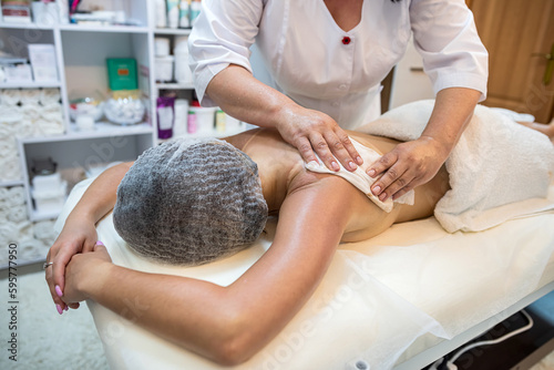 professional female masseuse massages a client's back on a massage table close-up.
