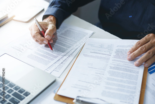 Asian businessman reviewing document reports at office workplace with computer laptop. legal expert, professional lawyer reading and checking financial documents or insurance contract