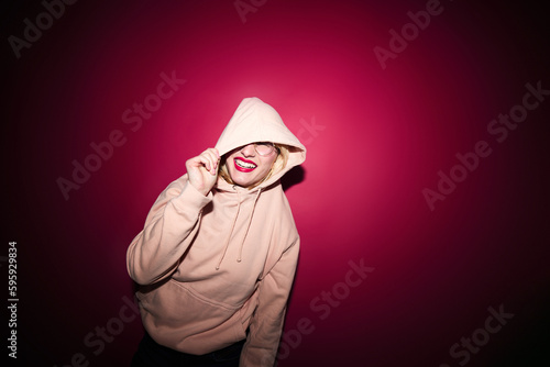 A cheerful young blond woman dancing in studio isolated on magenta background. Viva magenta, color of the year.
