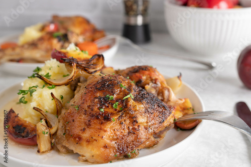 Baked chicken shanks with mashed potatoes, roasted onions and apples on a plate