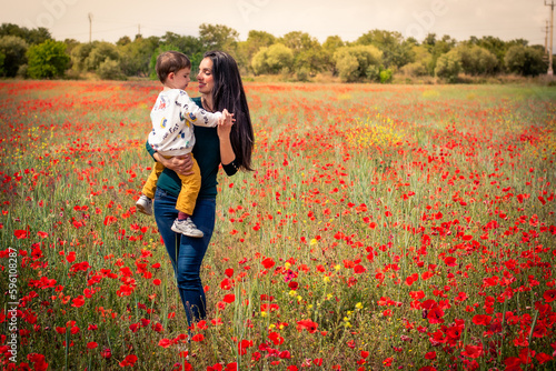 Mamá e hijo disfrutando en un campo de amapolas cogiendo flores