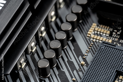 Macro shot of VRM MOSFETs and Capacitor (Voltage Regulator Module) on a modern motherboard. Mosfets, Solid-state capacitors, Chokes, Field-effect transistors, VRM. Technological background.