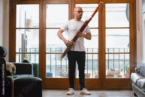 young latin man venezuelan musician in his living room standing playing the bassoon