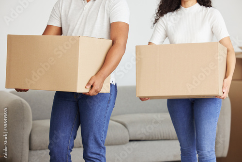 Ill help lighten the load for you. Shot of a young couple holding boxes in their new house.