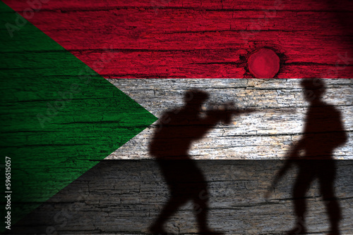 painting of the sudan flag on wood and the shadow of its soldiers.