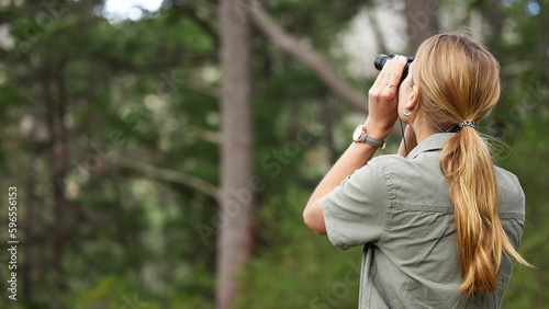 Binoculars, forest and woman explore in nature, travel journey or outdoor adventure for carbon footprint research. Watch, search and back person birdwatching in jungle, woods or eco green environment