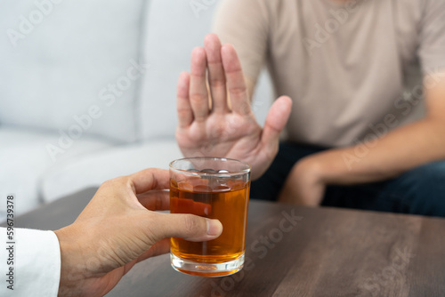 man refuses say no and avoid to drink an alcohol whiskey , stopping hand sign male, alcoholism treatment, alcohol addiction, quit booze, Stop Drinking Alcohol. Refuse Glass liquor, unhealthy, reject