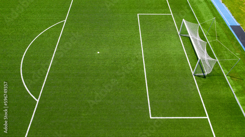 Aerial closeup of the penalty area on an empty synthetic grass soccer field. Here a penalty is taken in a soccer game.