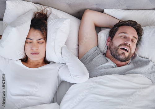 Make it stop. Shot of a young woman struggling to sleep with her boyfriends snoring at home.