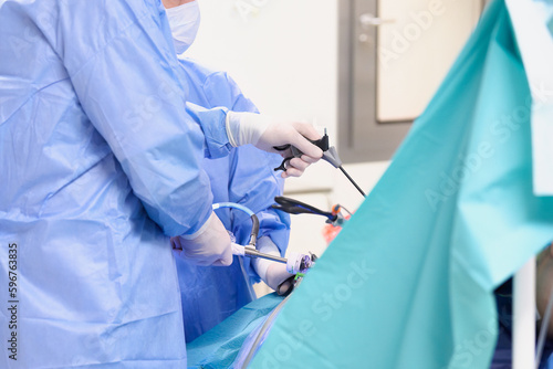 Operacja laparoskopowa na sali operacyjnej w szpitalu. Dłonie chirurga w sterylnych rękawiczkach trzymają narzędzia endoskopowe. Asysta instrumentariuszki.