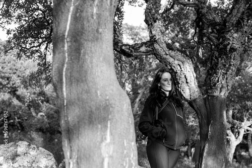 ragazza mora vestita di nero è immersa nella natura vicino a un albero secolare