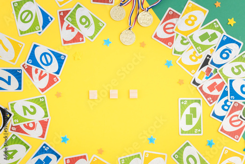 Old, dirty uno cards, winner medals, empty cubes and stars on a green-yellow background.