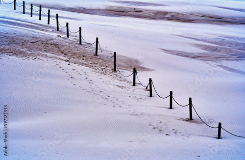 Shifting sand dune in national park near Leba with abstract graphic rope border on wooden poles