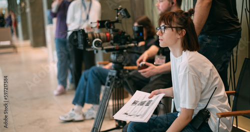 The director is a woman at work on the set. The director works with a group or with a playback while filming a movie