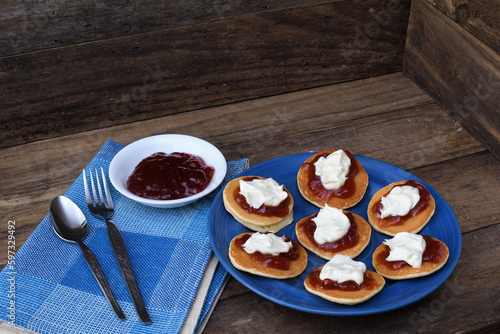 Pikelets Pancakes Battercakes strawberry jam whipped cream blue plate napkin spoon fork rustic wooden setting copy space