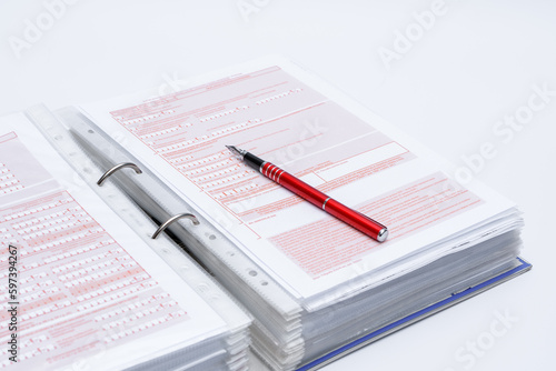 Segregator z dokumentami i leżący na nim czerwony długopis 