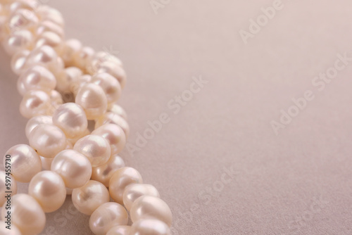 Elegant pearl necklace on beige background, closeup. Space for text