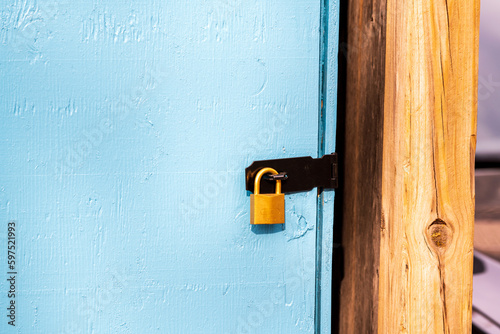  brass padlock securing a black metal hasp on a blue door room for text