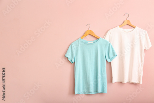 White and blue t-shirts hanging on pink wall