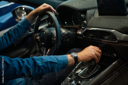 Close-up of a man's hand while shifting the automatic transmission of a car.