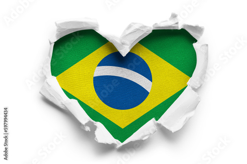 Heart shaped hole torn through paper, showing satin texture of flag of Brasil, cut out