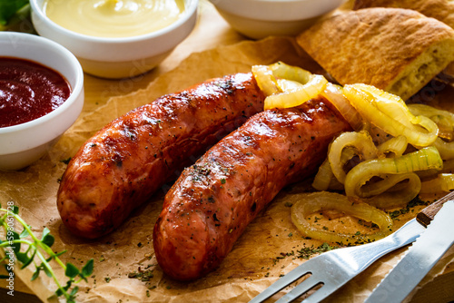 Fried sausages, onion and bread on wooden table 
