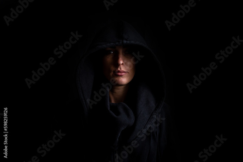 Young woman in a black hood on a black background