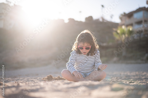 Excited girl playing in sand on beach