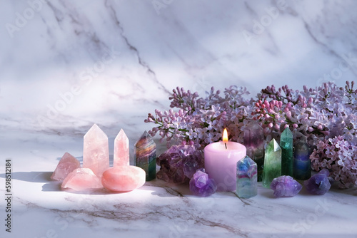 Gemstones set, candle, lilac flowers on marble background. gemstones for Healing Crystal Ritual, esoteric spiritual practice, aura cleansing, relax. reiki therapy. Fluorite, amethyst, rose quartz