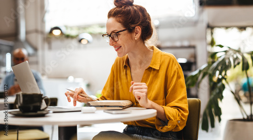 Female postgrad student student working on her thesis in a cafe