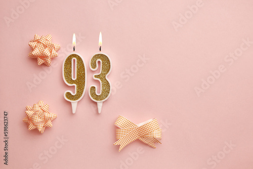 Candles with the number 93 on a pastel pink background with festive decor. Happy birthday candles. The concept of celebrating a birthday, anniversary, important date, holiday. Copy space. banner