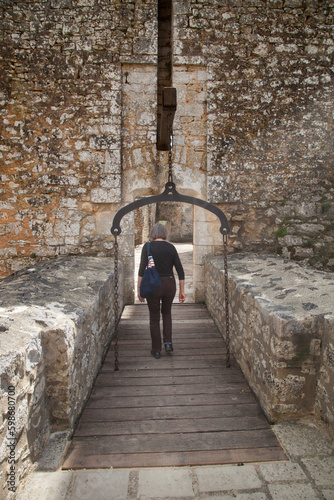 Femme touriste traversant le pont-levis pour pénétrer dans le château de Bonaguil (Lot-et-Garonne)