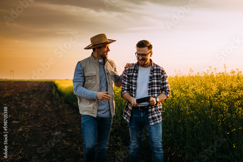 Two farmers walk across the field in countryside and discuss business