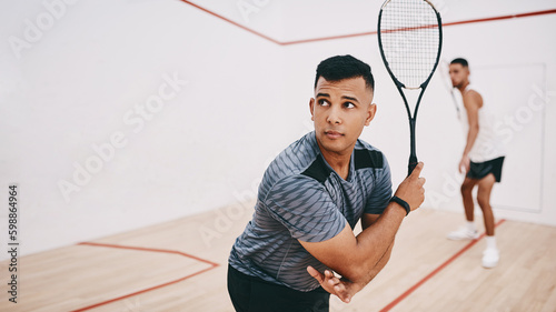 Play it to win it. two young men playing a game of squash.