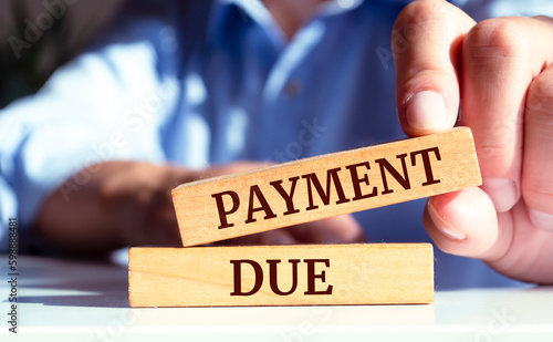 Close up on businessman holding a wooden block with a "Payment Due" message