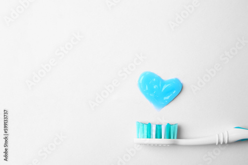 Heart made with toothpaste and brush on white background, top view. Space for text