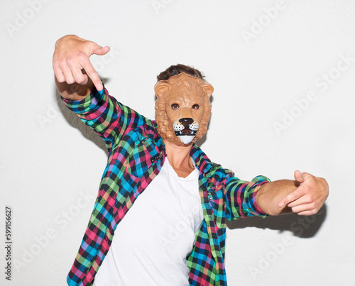 Animal mask, hand gesture and a man in studio with cool attitude to party with a positive mindset. Lion face or male model person isolated on a white background for fun, funny and goofy portrait