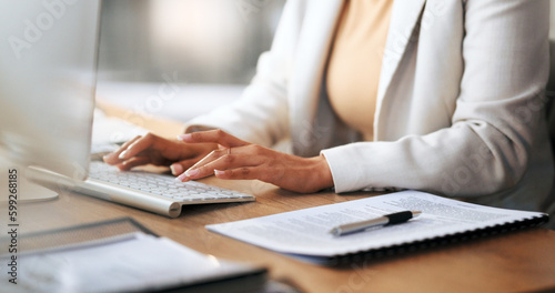 Closeup of the hands of a receptionist typing and sending emails while working in an office alone. One secretary doing admin and writing reports while organizing a schedule for her manager at work