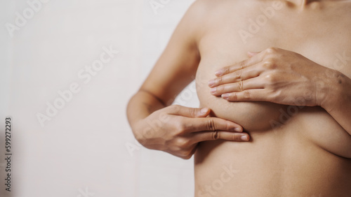 Young asian woman examining breast mastopathy or signs of breast cancer, Closeup Sexy Topless Naked Female With Breast Cancer Awareness