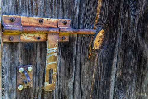 stara zardzewiała zasuwa na drewnianych drzwiach stodoły