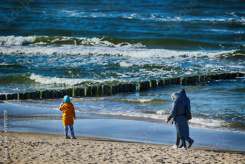 Ciepło ubrani ludzie na plaży nad morzem wiosną. 