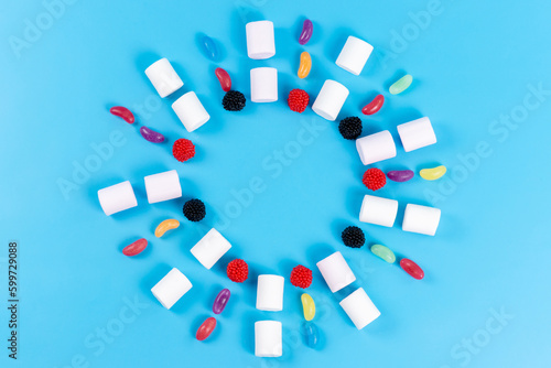 a top view marshmallows and marmalades lined on the blue background sugar confectionery children circle