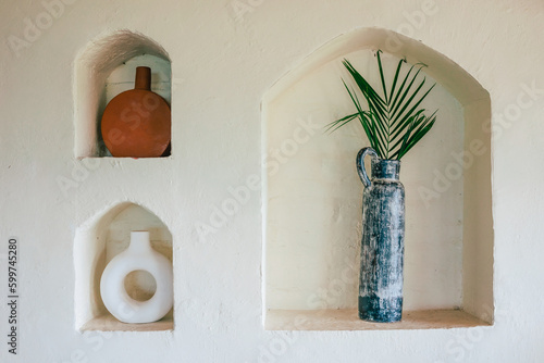 Frontal view of a mediterranean interior A white wall with three niches in which beautiful vases are placed.